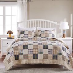 a bed with a white headboard and foot board in a bedroom next to a window