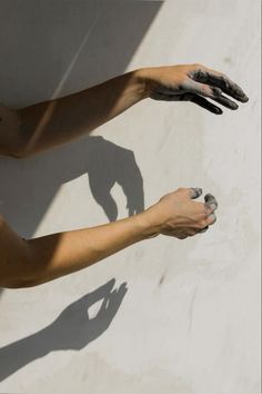 two hands holding something in the air with their shadow on the wall and one hand reaching for it