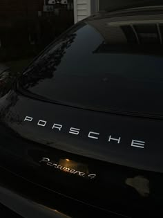 the back end of a black porsche parked in front of a house