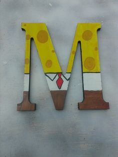 the letter m is made up of wood and painted like a cartoon character