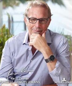 a man sitting at a table with his hand on his chin and looking to the side