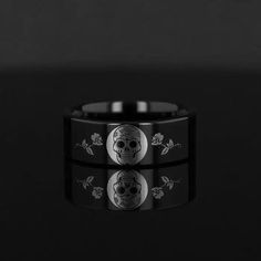 a black ring with skulls and roses on the inside, in front of a dark background