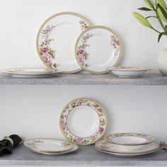 two shelves with plates and flowers on them, one has a vase in the background