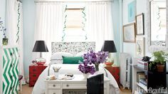 a bedroom decorated in green and white with purple flowers on the bed, two black lamps