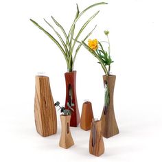 three wooden vases with flowers in them on a white surface, one is made out of wood