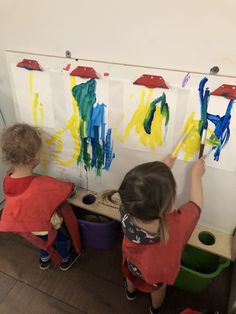 two children are painting on the wall