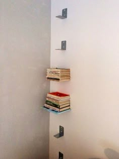 three books are stacked up on the wall next to each other in a corner near a toilet