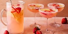 three glasses filled with drinks and strawberries sitting on a table next to each other