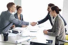 three business people shaking hands over a table