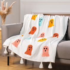 a couch with a blanket on top of it that has ghost faces drawn on it