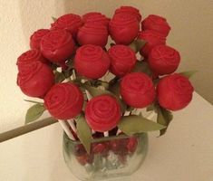 a vase filled with red roses on top of a white table next to a wall