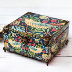 an ornately painted wooden box sitting on top of a white wood floor next to a pair of scissors