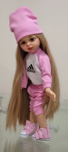 a doll with long blonde hair wearing pink pants and a beanie on her head