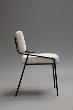 a white chair sitting on top of a gray floor next to a black metal frame