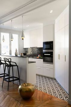 an open kitchen with white cabinets and black counter tops, along with two stools