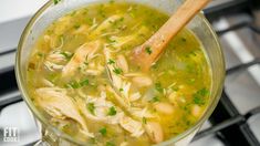 a wooden spoon in a pot filled with chicken and noodle soup on the stove