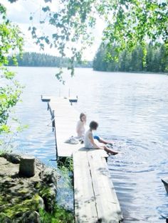 two children are sitting on a dock by the water