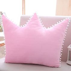 a pink pillow sitting on top of a white chair