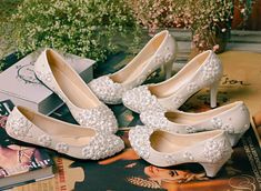 three pairs of white high heel shoes with pearls on the toes and heels are sitting next to each other