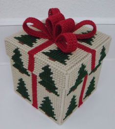 a knitted christmas present box with a red bow on it's top and green trees