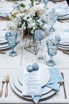 the table is set with blue and white plates, silverware, and flowers in vases