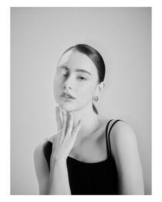 a black and white photo of a woman with her hand on her face