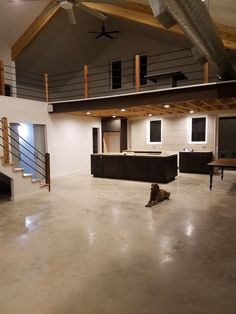 a dog is laying on the floor in an empty room with exposed ceilings and stairs