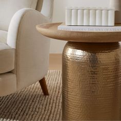 a table with a book on top of it next to a chair and ottoman in a living room