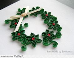 an origami christmas wreath made out of rolled up green paper with red berries