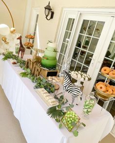 a table topped with lots of food and desserts next to a window filled with glass doors