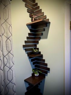 a wooden shelf sitting on the side of a wall next to a plant in a vase