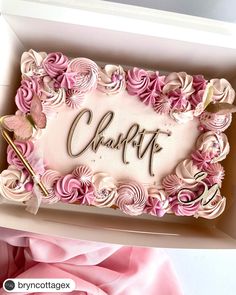 a cake in a box with the word charlotte written on it and pink flowers all around