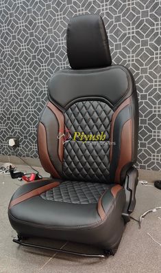 a black and brown leather car seat sitting on top of a floor next to a wall