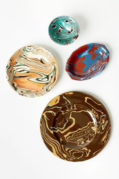 three marbled bowls sitting on top of a white table next to an empty plate