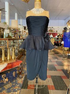 Vintage 1980s dress 80s cocktail / formal Strapless fitted bodice Ruched black silk jersey Ruffled chiffon peplum waist Wrap style skirt Huge rosette on the hip Lined in nylon By Jill Richards Size small Bust 32/34" Waist 26" Hips to 38"   Very good vintage condition *Jill Richards was an American designer from California, active from 1970 to the 1990s. Known for very feminine clothing in luxury fabrics, she was nicknamed "Ruffles Richards," and counted among her clientele Hollywood stars as wel Chiffon Wrap Skirt, Feminine Clothing, Nancy Reagan, Cocktail Formal, Jersey Vintage, Chiffon Wrap, 1980s Dresses, 80s Dress, Black Jersey