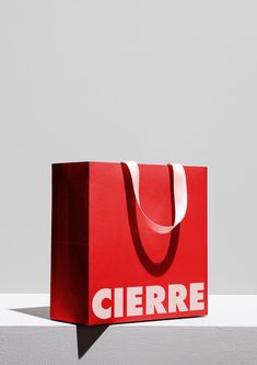 a red shopping bag with the word ciere on it sitting against a white wall