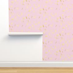 a pink wall with gold confetti on it next to a white door and wooden floor