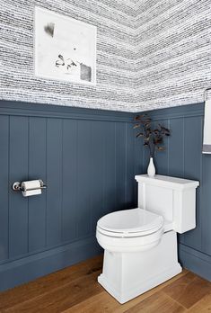 a white toilet sitting in a bathroom next to a wall with blue paint on it