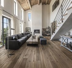 a living room filled with furniture and a fire place next to a stair case in front of a window