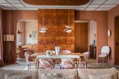 a living room filled with furniture and a dining table in front of a wooden paneled wall