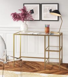 a desk with a chair, lamp and pictures on the wall in a living room