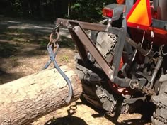 a tractor is parked next to a tree log and has chains attached to the front