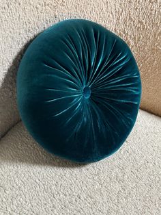 a blue round pillow sitting on top of a white couch next to a beige wall