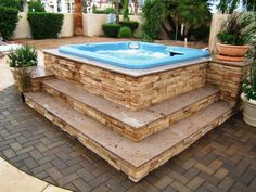 an outdoor hot tub with steps leading up to it and potted plants in the background