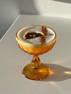 a dessert in a glass on a white table with a shadow from the light coming through it