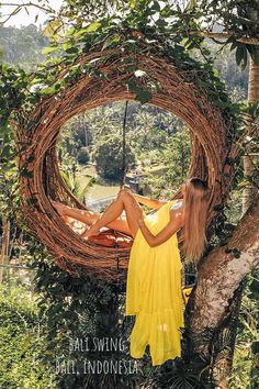 a woman in a yellow dress sitting on top of a tree next to a wreath