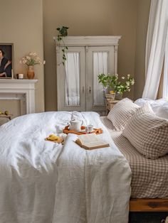 a bed with white linens and pillows in a bedroom next to a fireplace,