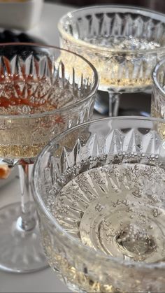 three wine glasses filled with liquid on top of a table