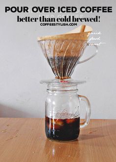 a glass coffee maker filled with liquid on top of a wooden table