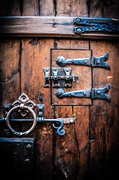 an old wooden door with metal handles and latches